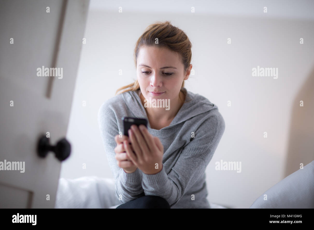 Junge Erwachsene weiblichen Kontrolle Smartphone am Morgen Stockfoto