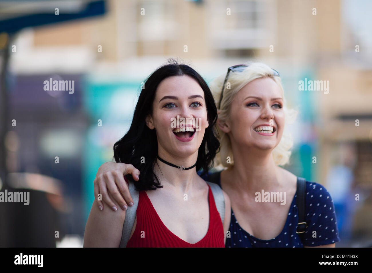 Weibliche Freunde gehen auf eine Straße mit Geschäften im Sommer Stockfoto