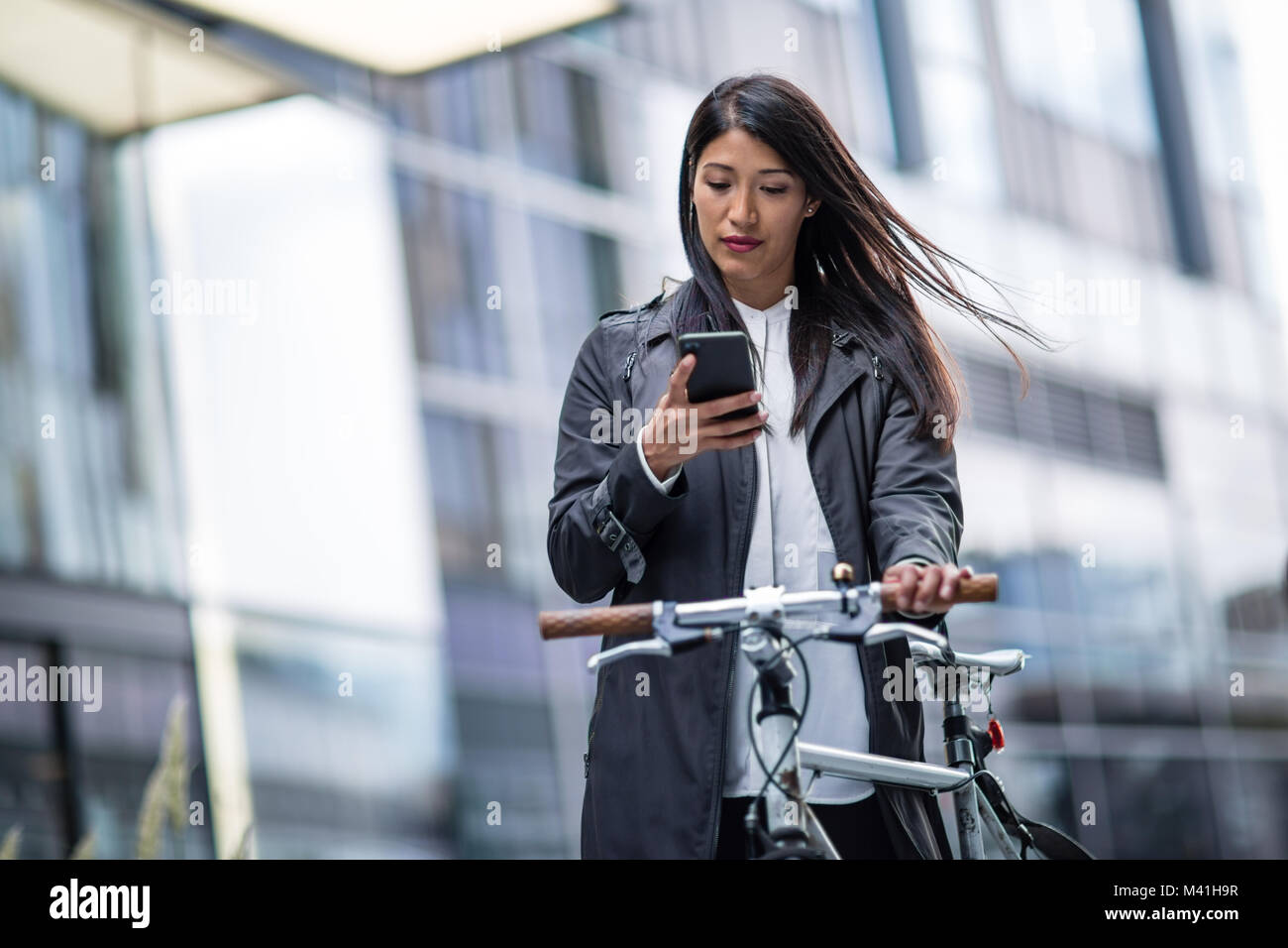 Geschäftsfrau Radfahren mit Smartphone zu arbeiten Stockfoto