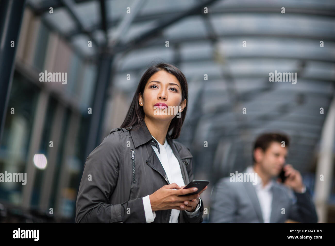 Geschäftsfrau warten auf Zug auf Plattform mit Smartphone in der Hand Stockfoto