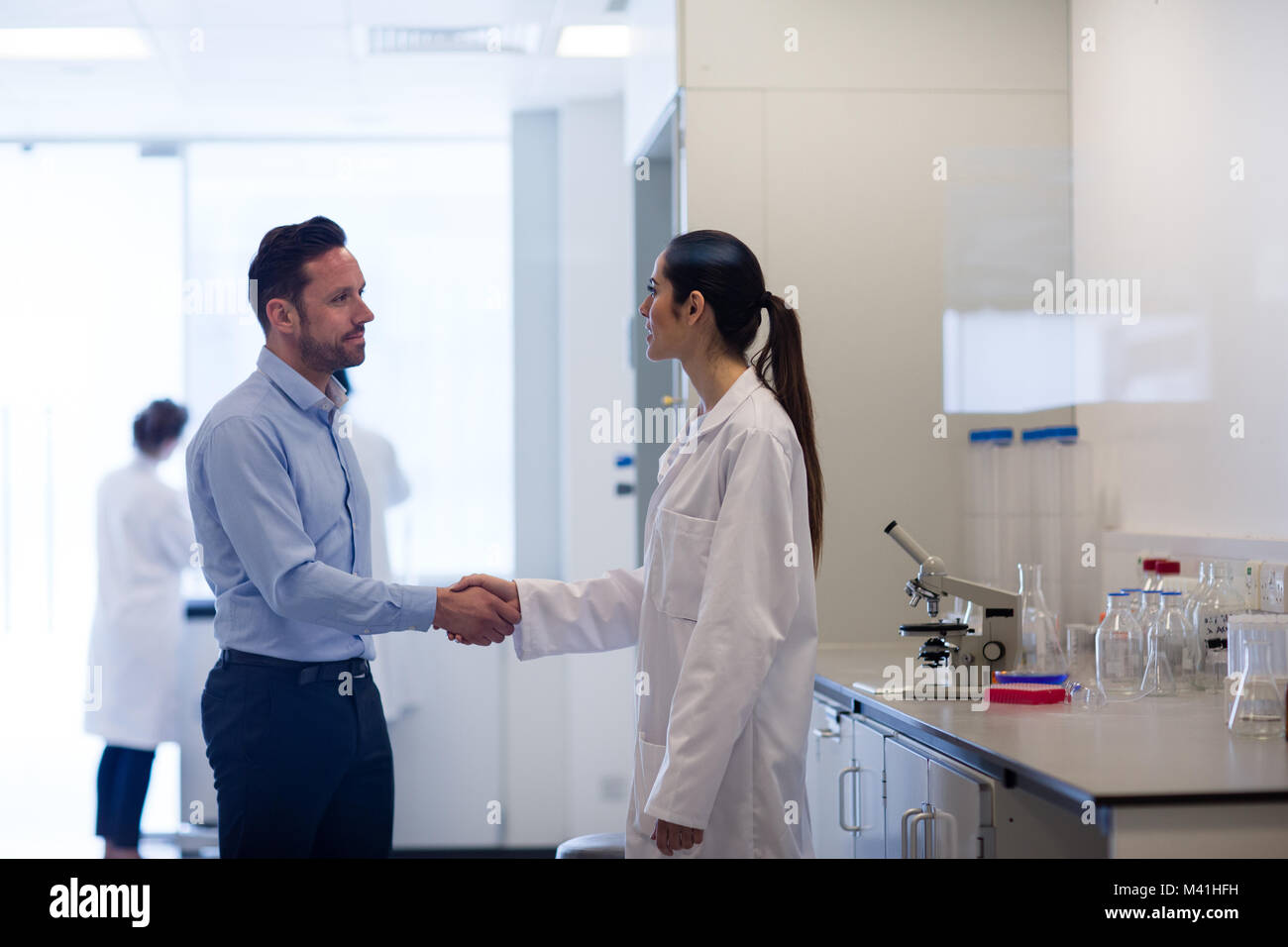Wissenschaftlerin Händeschütteln mit pharmazeutischen Vertriebsmitarbeiter Stockfoto