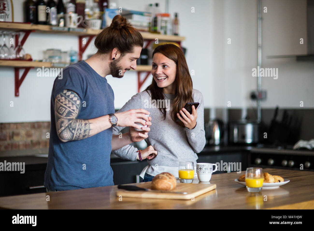 Junges Paar an Smartphone zusammen mit Blick auf Frühstück Stockfoto