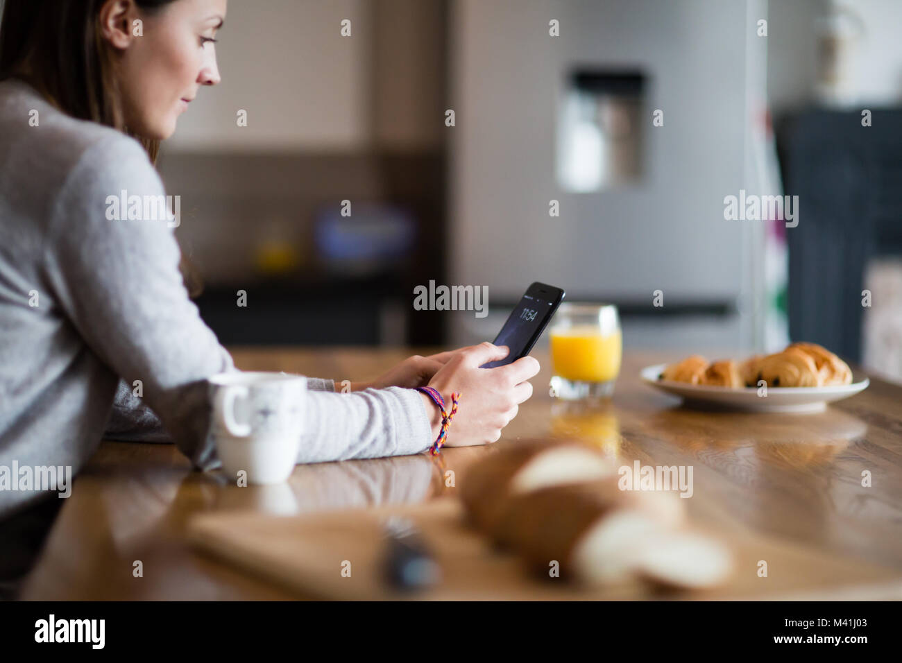 Junge erwachsene Frau in Kaffee am Morgen und Smartphone Stockfoto