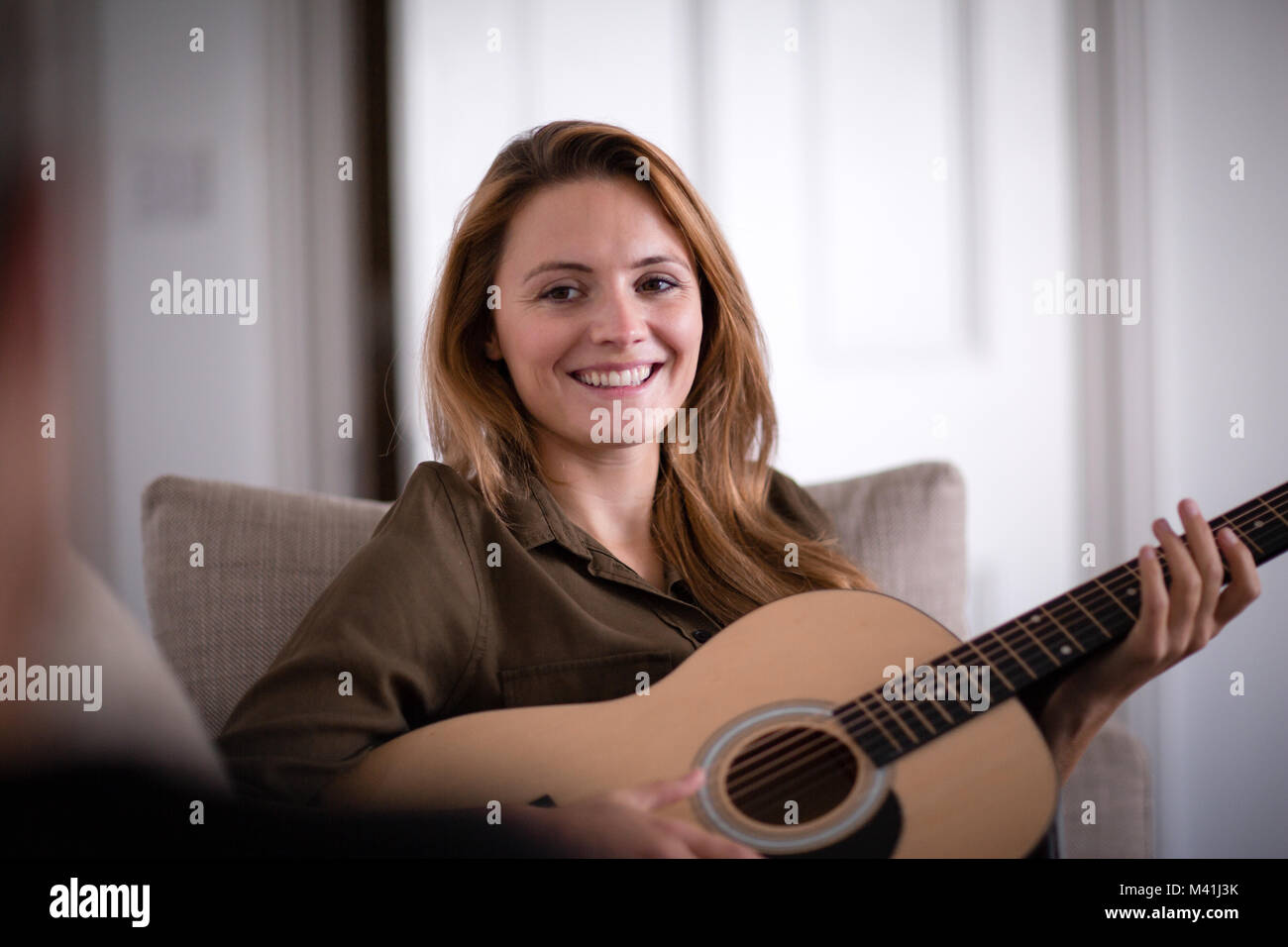 Junge erwachsene Frau spielen akustische Gitarre zu Freund Stockfoto