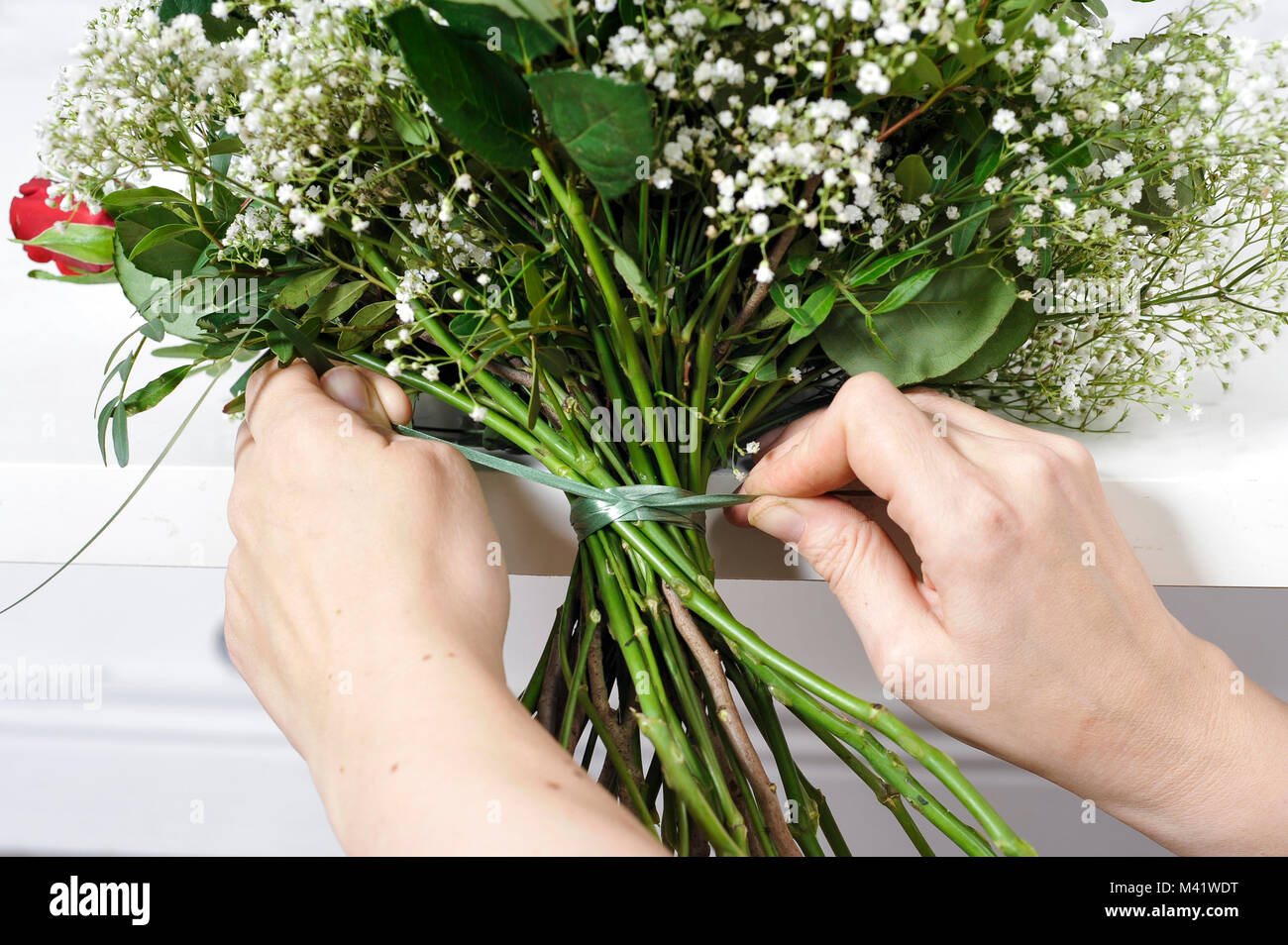 Buches von Blumen für einen besonderen Anlass wie Valentinstag angeordnet wird. Frau trimmen die Stiele der Blumen nach anordnen. Stockfoto