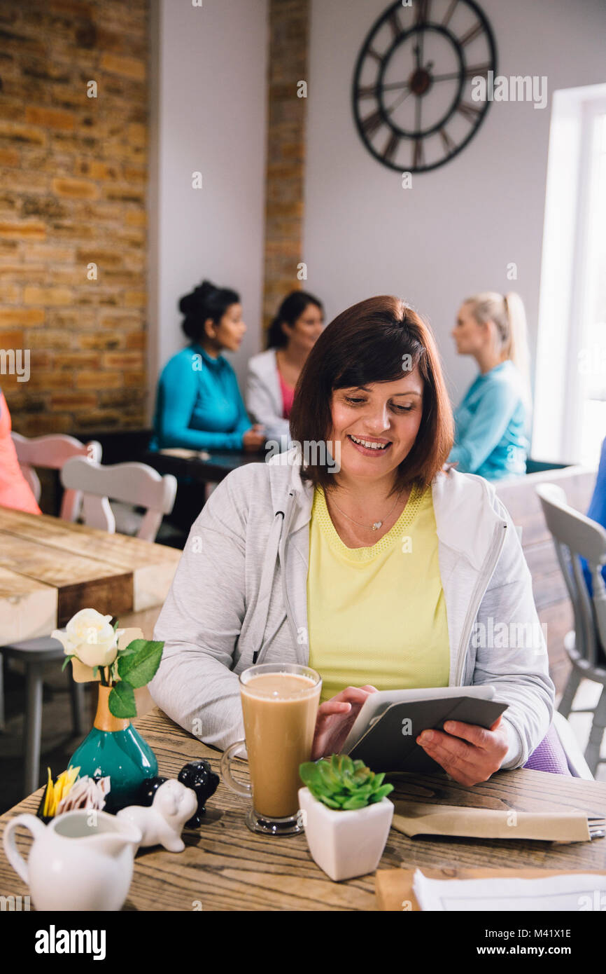 Reife Frau sitzt in einem Cafe mit einem digitalen Tablet bei einer Tasse Kaffee. Stockfoto Reife Frau sitzt in einem Cafe mit einem digitalen Tablet bei einer Tasse Kaffee. Stockfoto