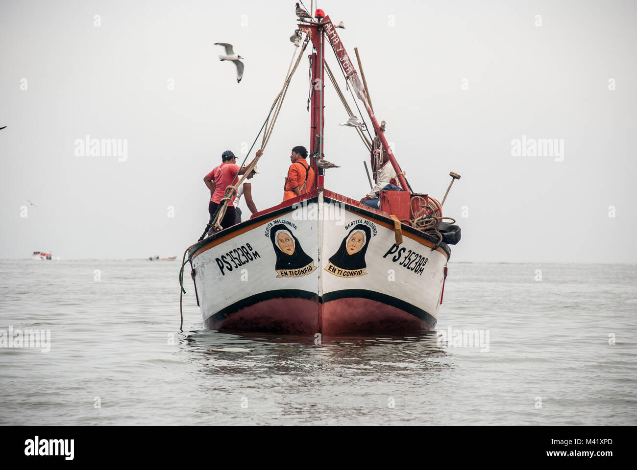 Fischer stehen und sprechen über ein Fischerboot auf dem Meer in Peru Stockfoto