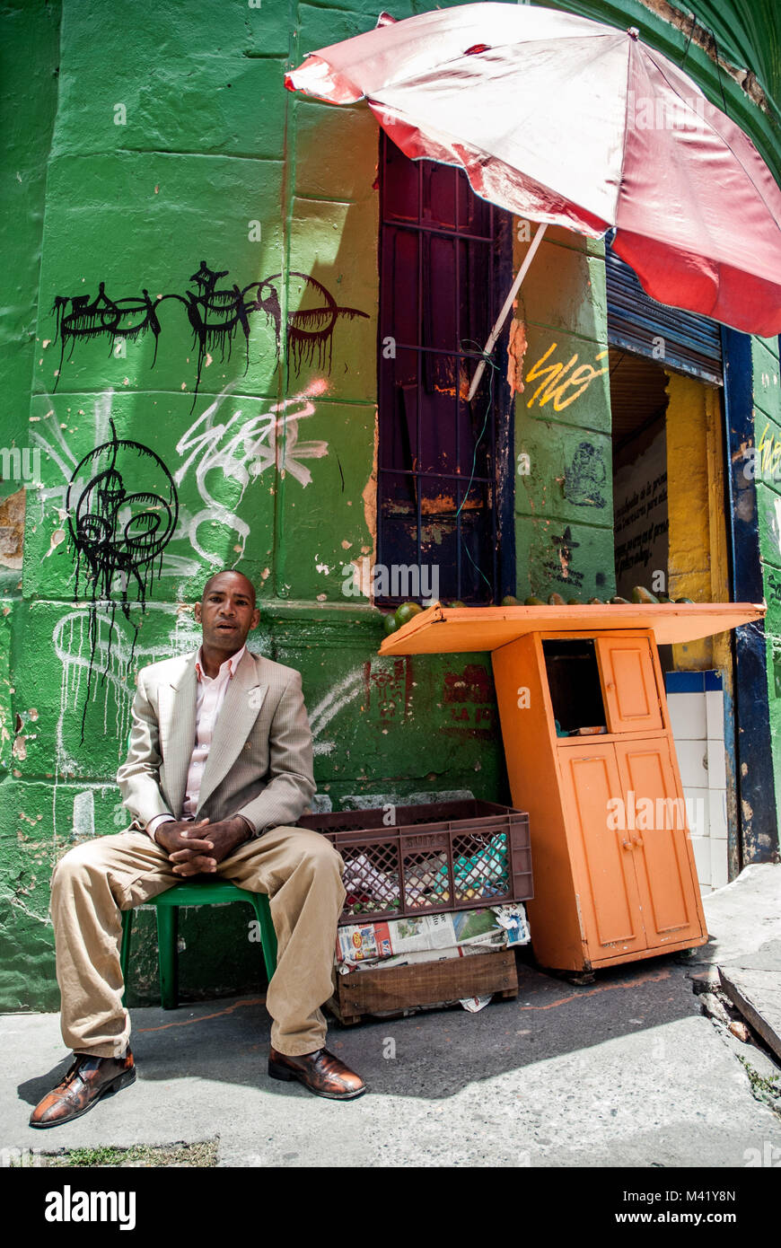 Ein schwarzer Mann im Anzug verkaufen avocados aus seinem Stall auf den Straßen von Bogotá, Kolumbien gekleidet Stockfoto
