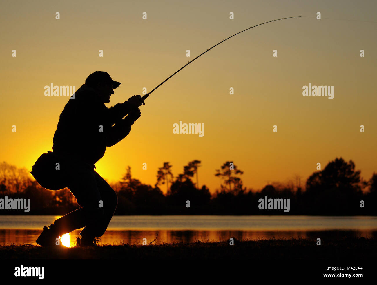 Eine Baß-Fischer Kampf gegen einen Fisch bei Sonnenuntergang Stockfoto