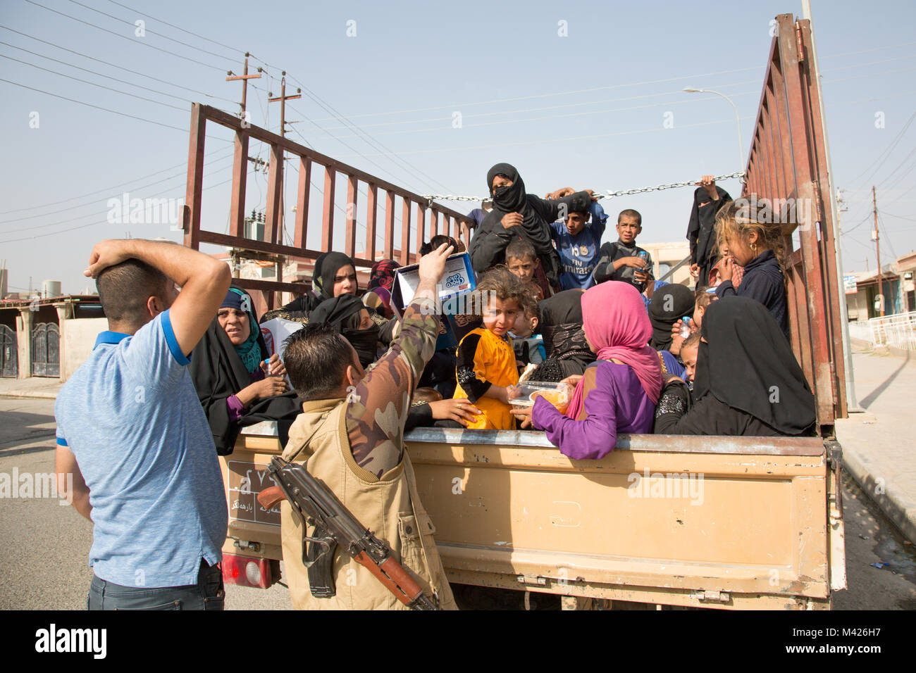 Ein peshmerga Soldat der intern Vertriebenen zu einem Screening Punkt verläuft, Wasser, dass er sein eigenes Geld verwendet für die Gruppe in der Nähe von Dibis, Irak, 30. September 2017, das transportiert wird, zu kaufen. Die internationale Hilfe Gruppen arbeiten mit der Regierung des Irak zu Hilfe und Unterstützung für Binnenvertriebene zur Verfügung zu stellen. Die Regierung Iraks und die lokalen Regierungen in Zusammenarbeit mit der internationalen Gemeinschaft arbeiten Dienstleistungen und kehren die Menschen in ihre Häuser so schnell wie möglich wiederherzustellen. (U.S. Armee Foto von Sgt. Tracy McKithern) Stockfoto