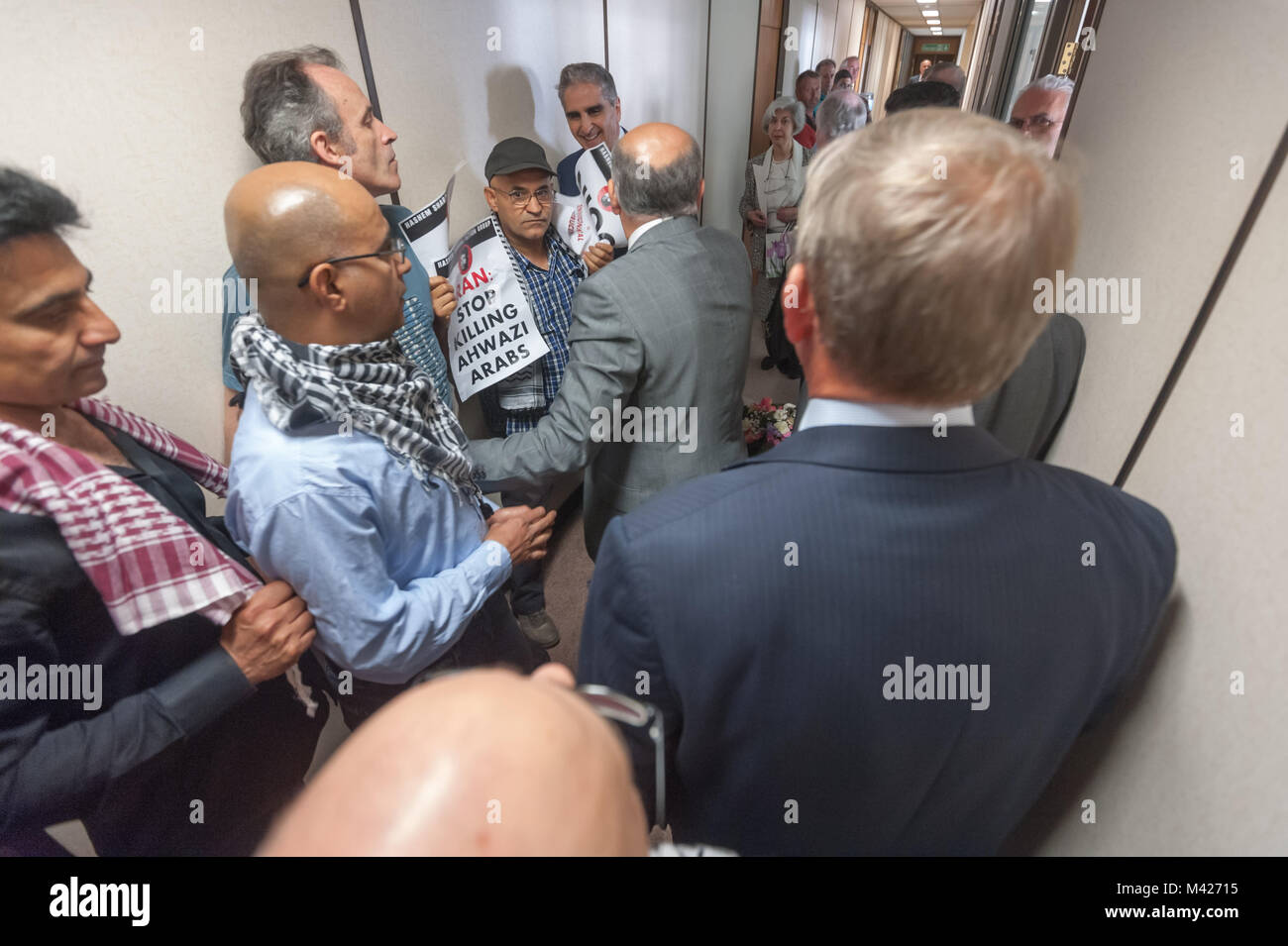 Die Demonstranten und Menschen aus dem geheimen UK-Iran business meeting in NIOC argumentieren im Korridor vor der Sitzung. Stockfoto