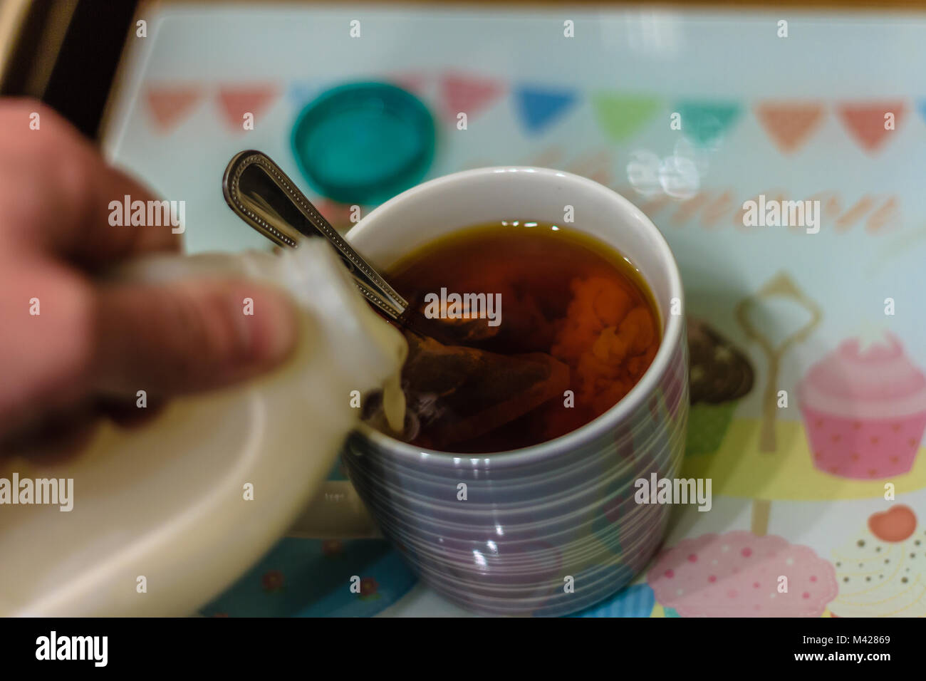 Milch wird in einen Becher Kaffee hinzugefügt. Stockfoto