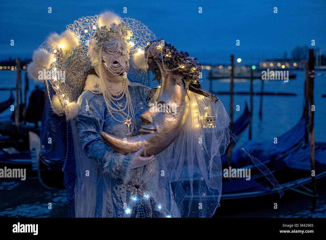 Frau in Kostüm und Maske fotografierte in der Dämmerung an der Karneval von  Venedig. Ein Mond mit Zurück zu den Grand Canal, Gondeln im Hintergrund  Stockfotografie - Alamy