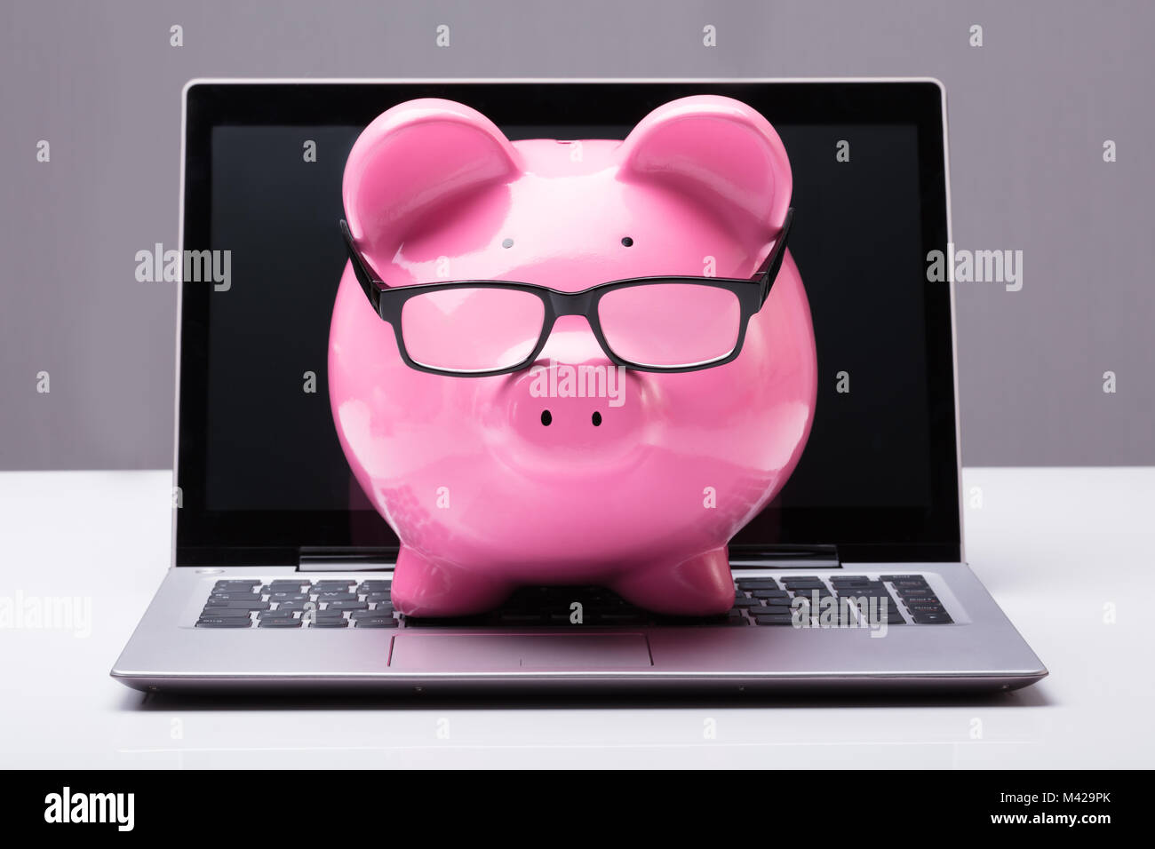 Sparschwein mit Brillen auf Laptop in Geld sparen Konzept Stockfoto