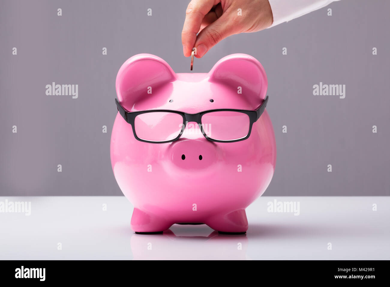 Geschäftsmann einfügen Münze in Geld sparen Konzept auf Schreibtisch Stockfoto