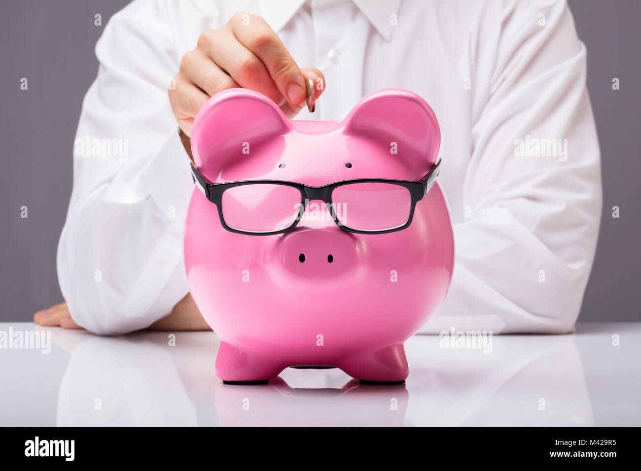 Geschäftsmann einfügen Münze in Geld sparen Konzept auf Schreibtisch Stockfoto Geschäftsmann einfügen Münze in Geld sparen Konzept auf Schreibtisch Stockfoto