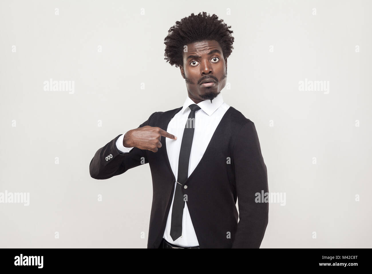 Verwunderung aloof afro Mann an der Kamera schaut und Zeigefinger sich. Studio shot, grauer Hintergrund Stockfoto