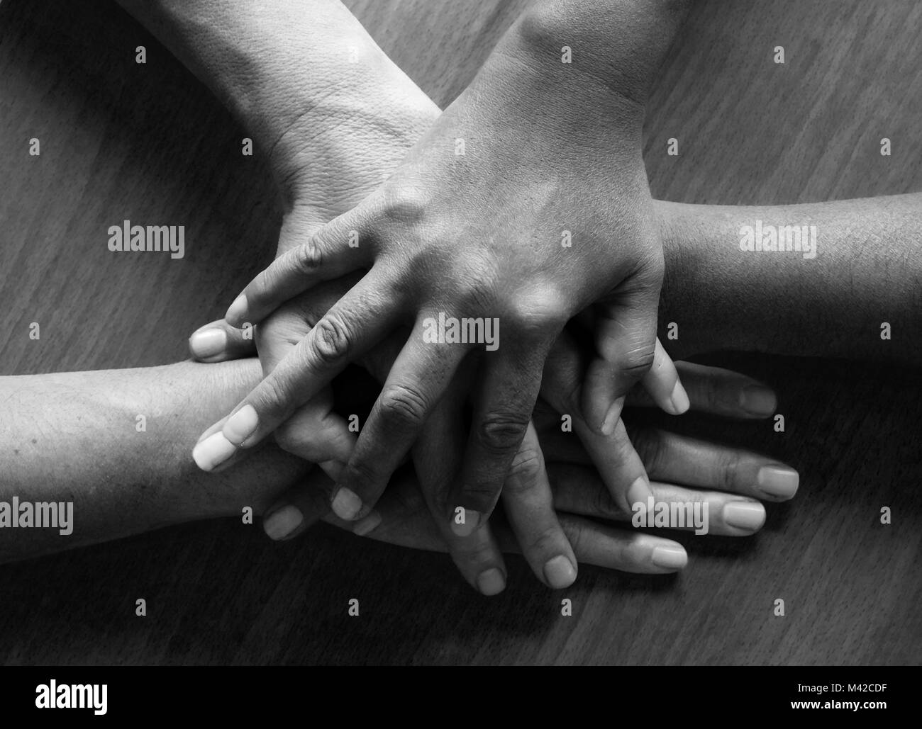 Auf vier fünfzig Jahre alte weibliche Hände ontop gelegt, die obere Hand und dritte Hand sind asiatische und die zweite und die vierte Hand sind Stockfoto