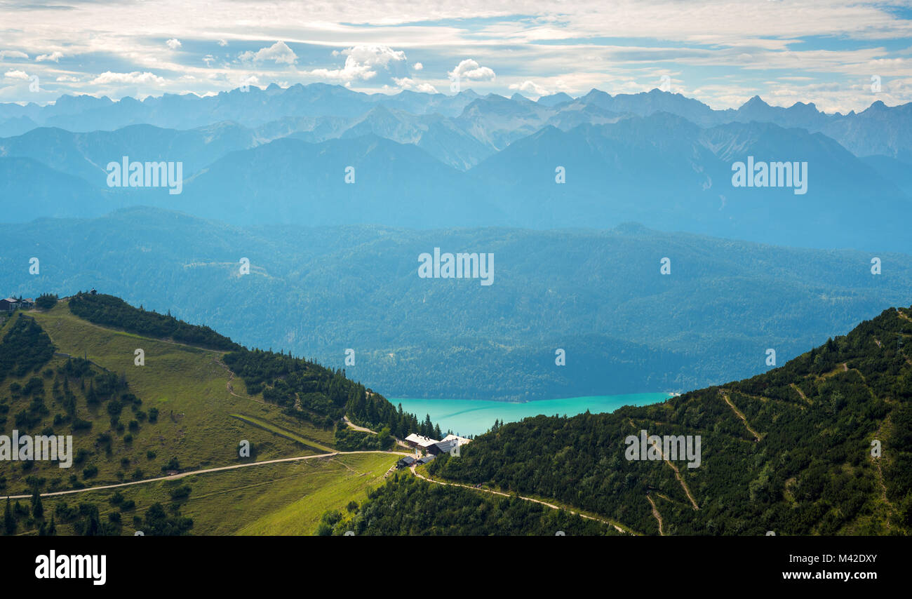 Fernsicht auf Gästehaus auf Wanderweg in den Alpen gegen turqiose See und Bergrücken Stockfoto
