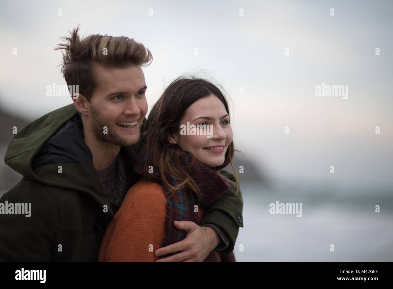 Junge Erwachsene Paar umarmen am Strand Stockfoto