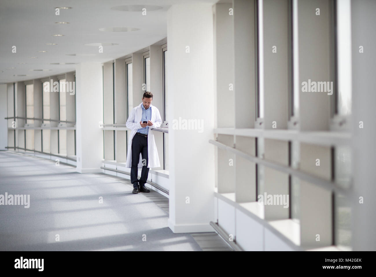 Männliche Mediziner mit Smartphone im Korridor Stockfoto