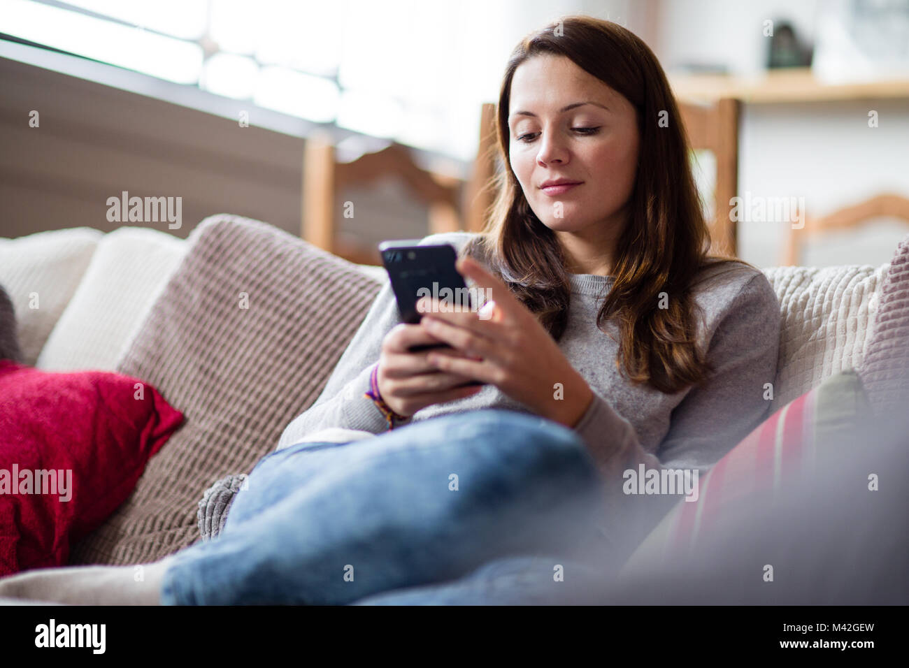 Junge erwachsene Frau mit Smartphone Sofa Stockfoto