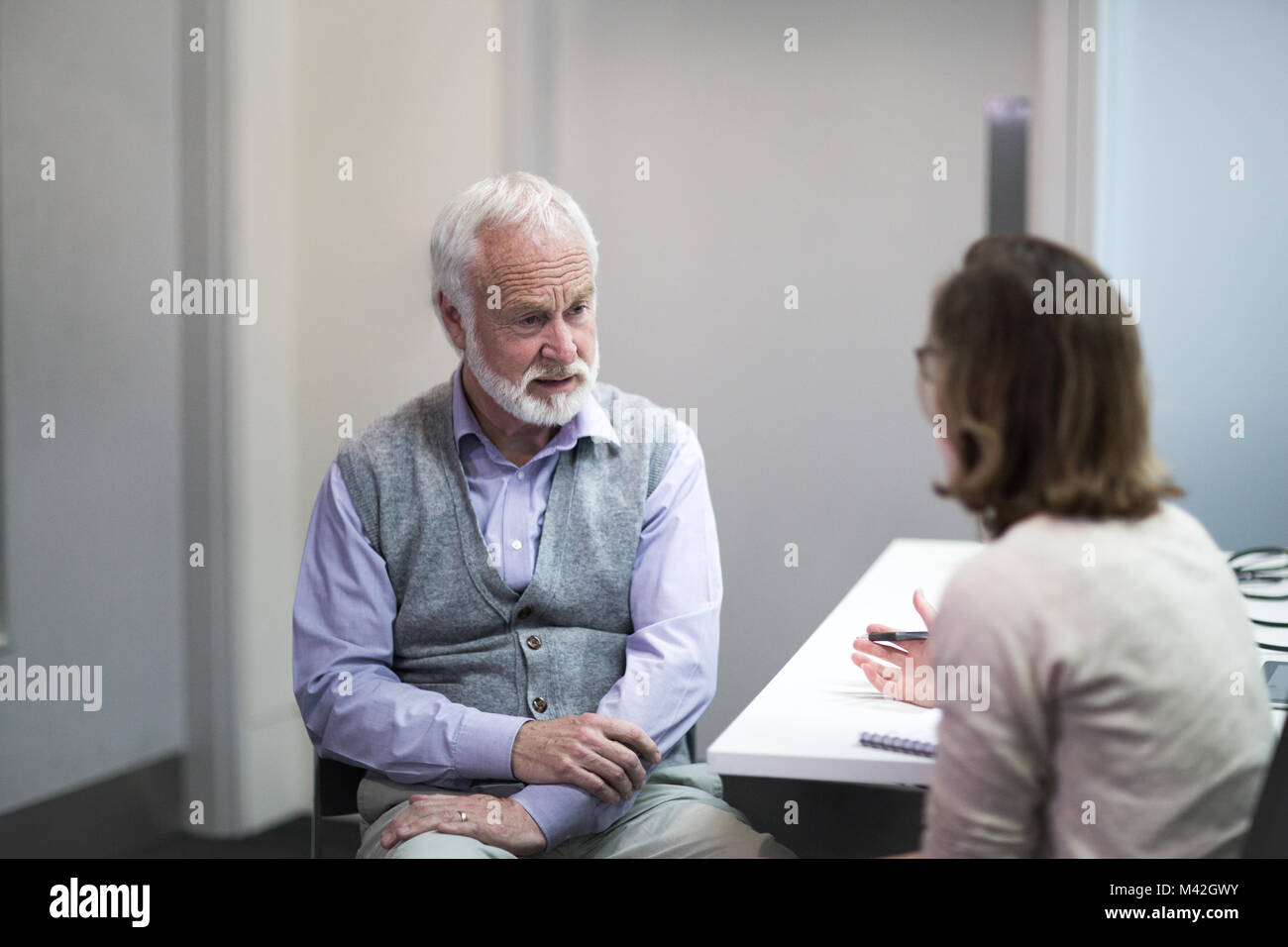 Weibliche Arzt hören ein älterer Patient Symptome Stockfoto