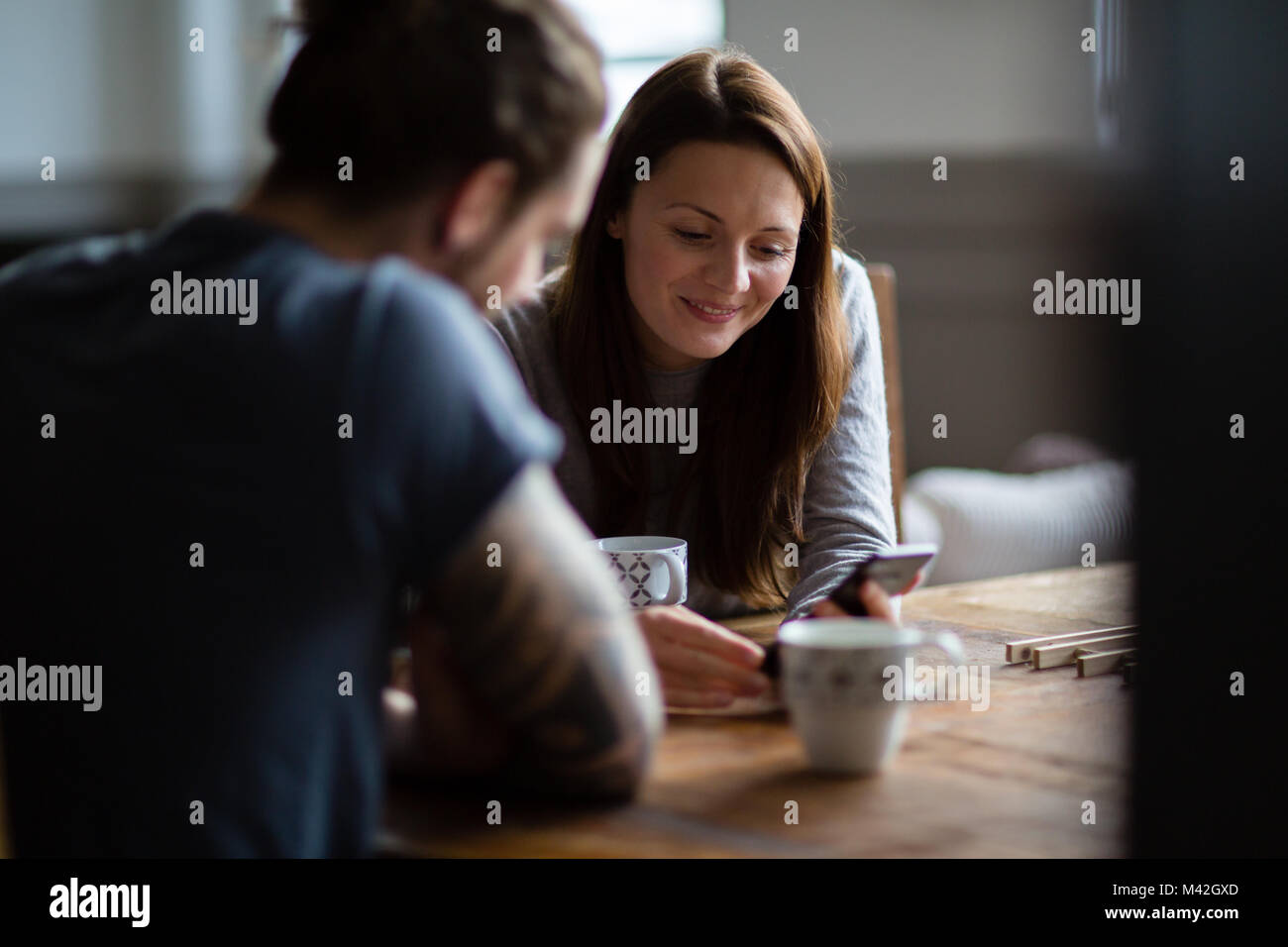 Junge Erwachsene Paar in einem cafŽ zusammen an einem Smartphone suchen Stockfoto