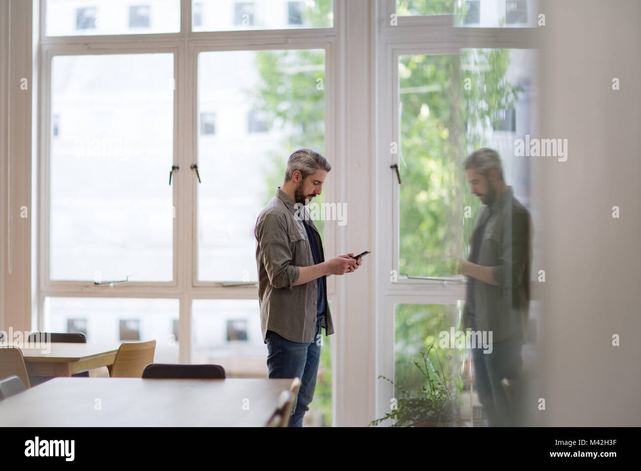 Unternehmer im leeren Büro auf Smartphone Stockfoto