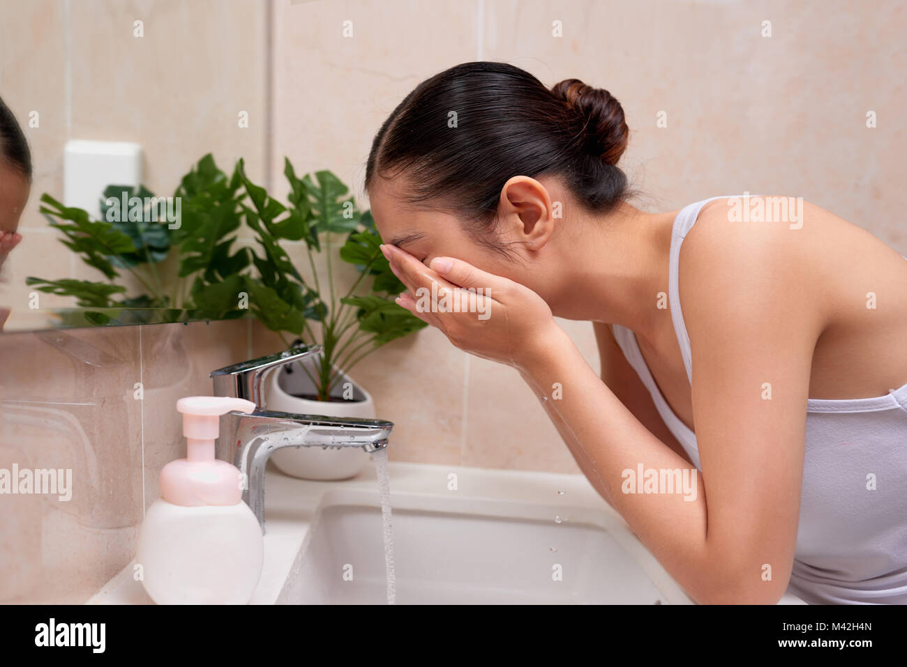 Asiatische junge Frau ihr Gesicht waschen am Waschbecken Stockfoto