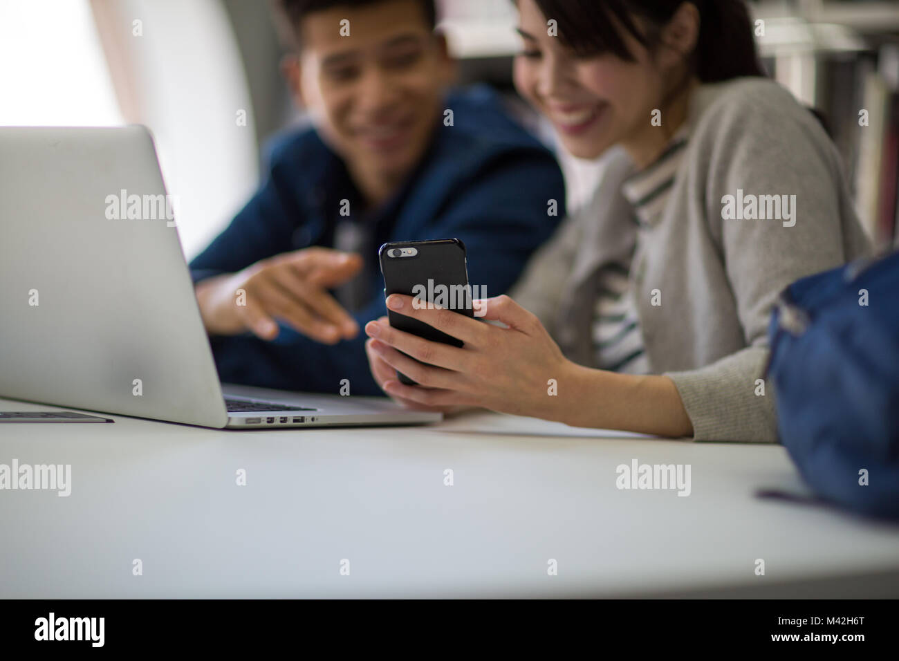 Studenten, die an Smartphone in Bibliothek Stockfoto