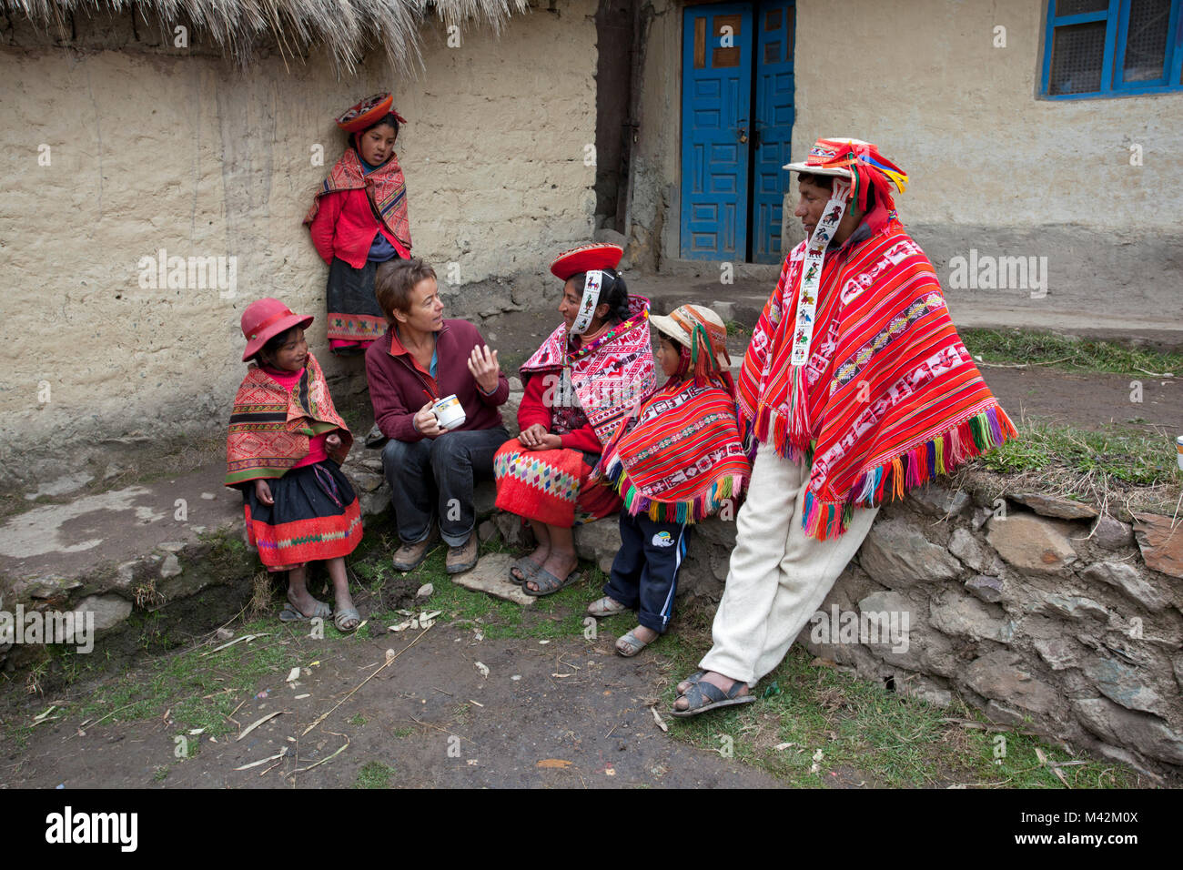 Peru, Patakancha, Patacancha, Dorf in der Nähe von Ollantaytambo. Indische Familie in traditioneller Kleidung und touristische, Frau, in Gespräch. Stockfoto