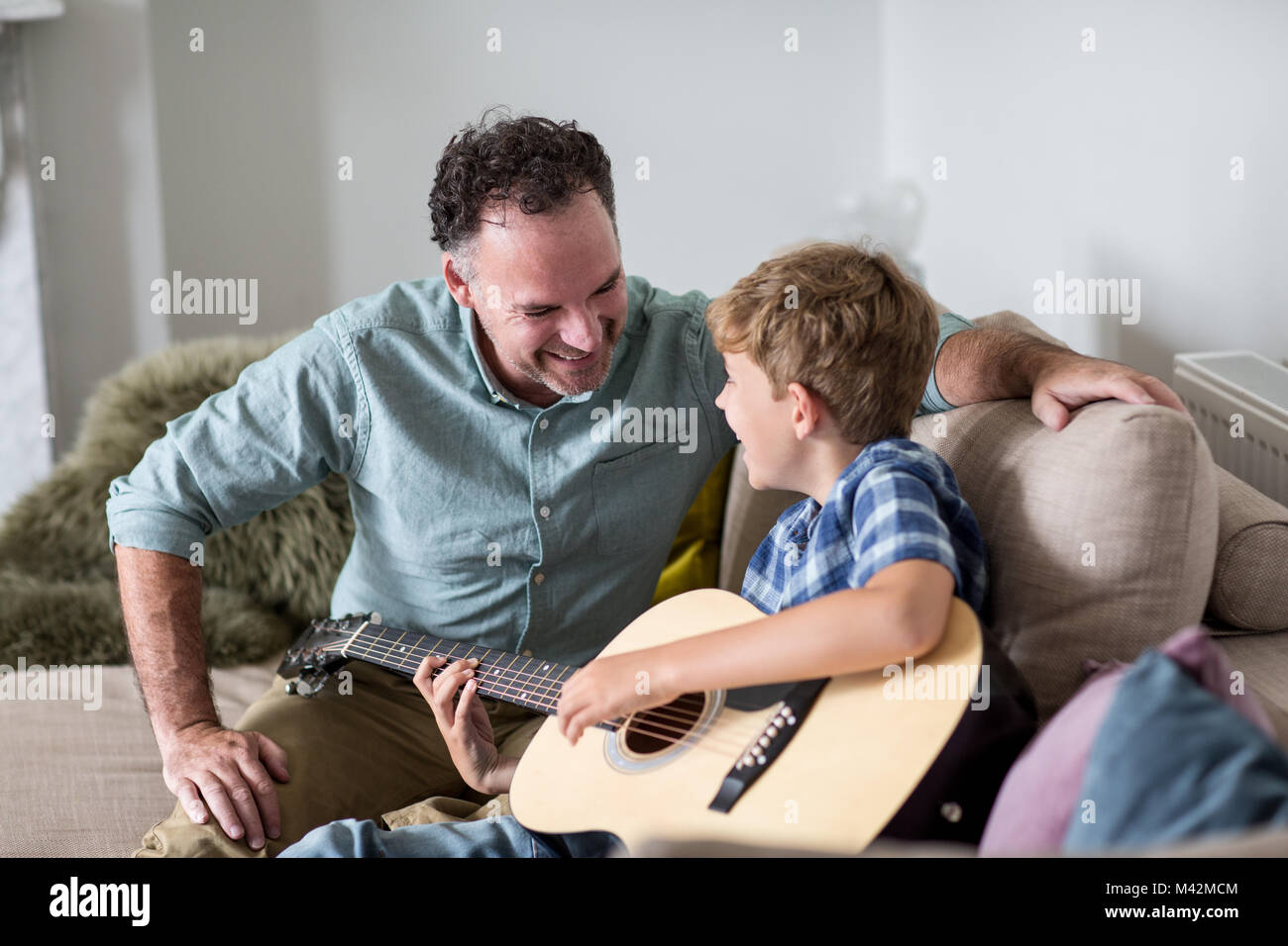 Sohn Gitarre spielen mit Vater Stockfoto