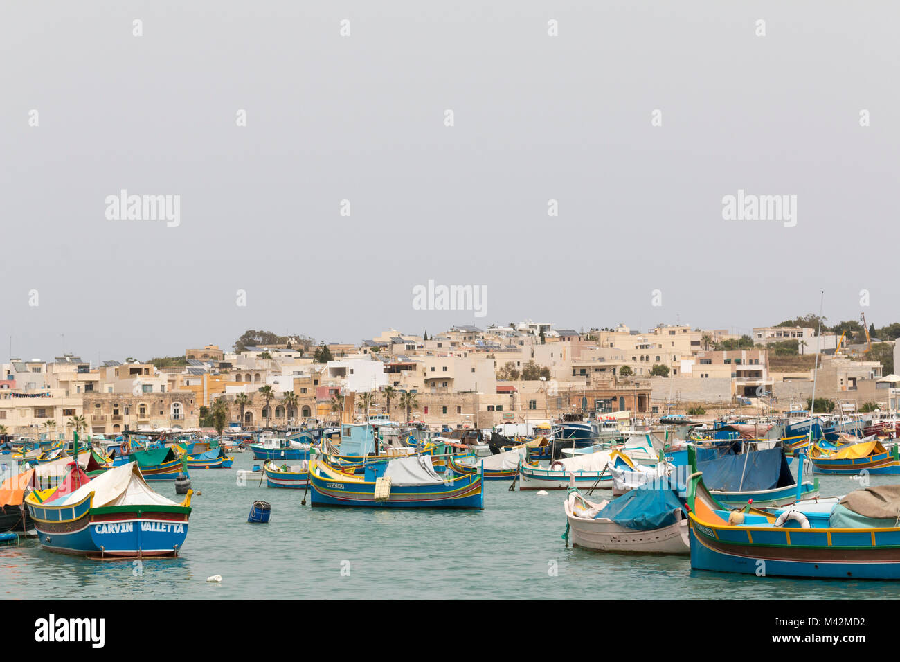 Ein Bild von einem Fischerdorf mit traditionellen Luzzu Boote im Vordergrund, Marsaxlokk, Malta Stockfoto