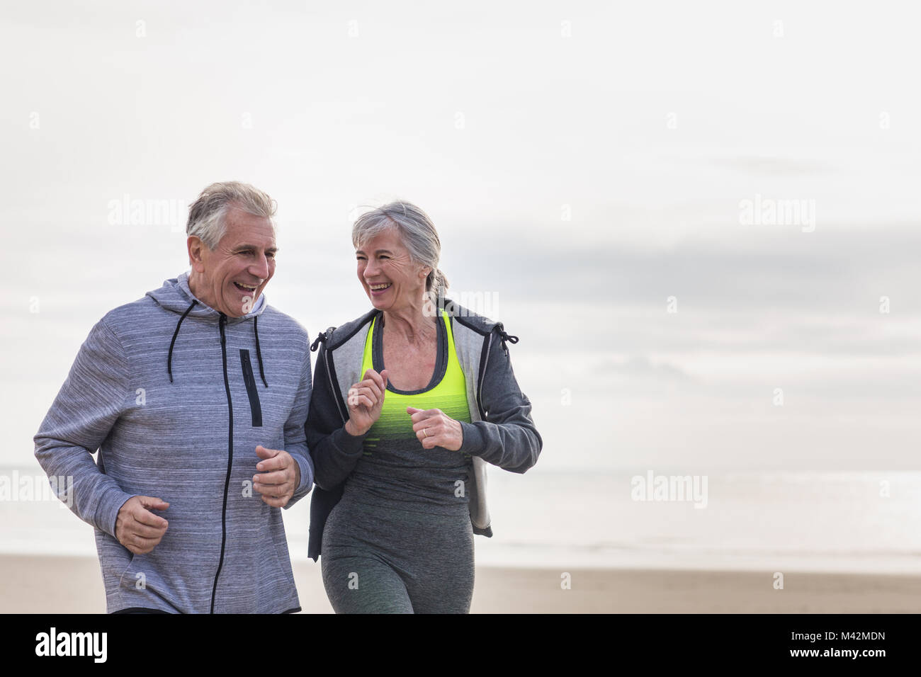 Älteres paar jogging am Strand Stockfoto