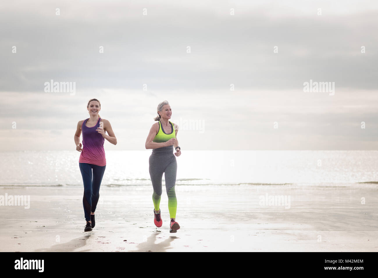 Active Senior Frau mit Tochter am Strand Stockfoto
