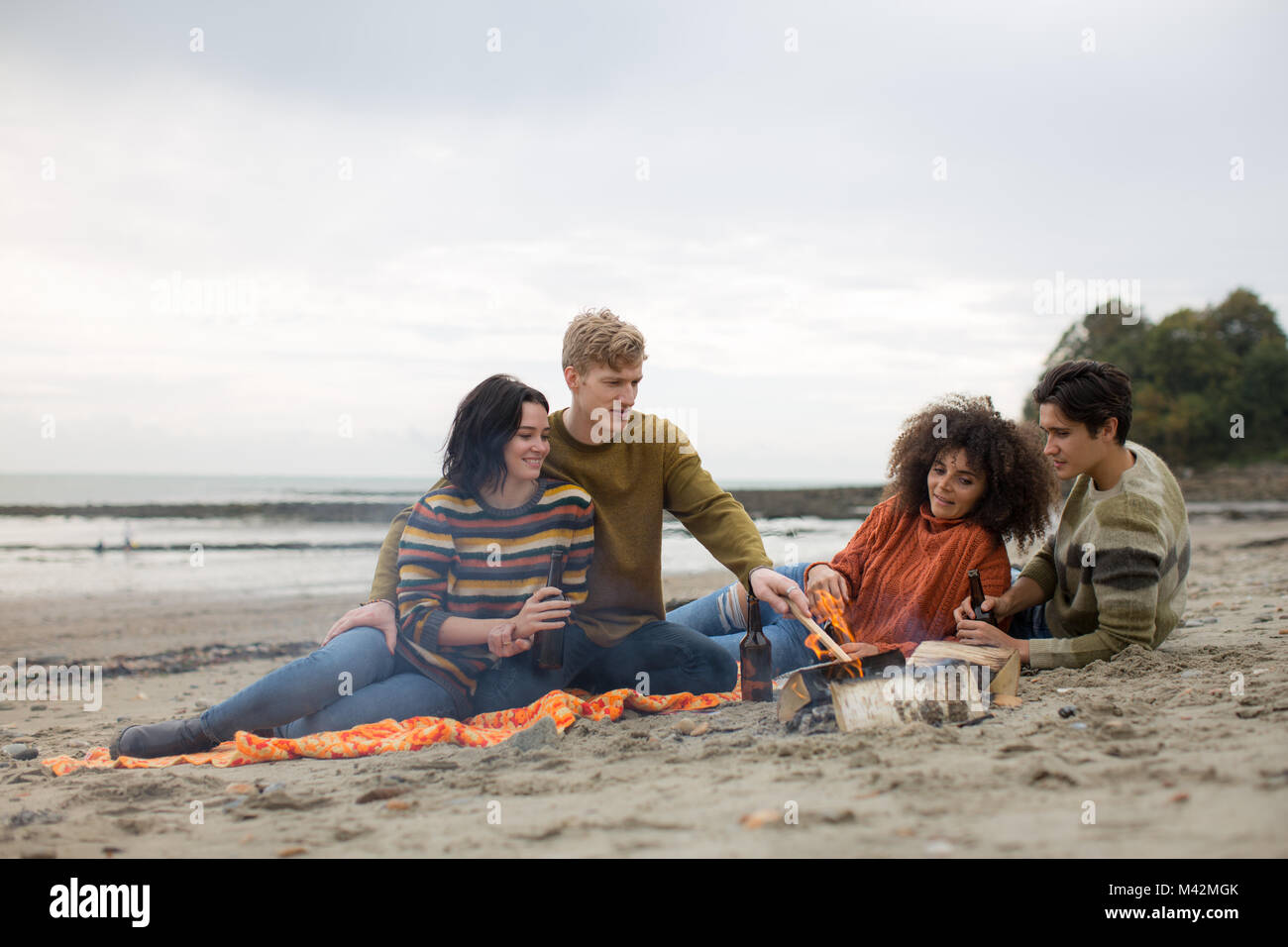 Gruppe für junge Erwachsene sitzen um das Feuer auf Winterurlaub Stockfoto