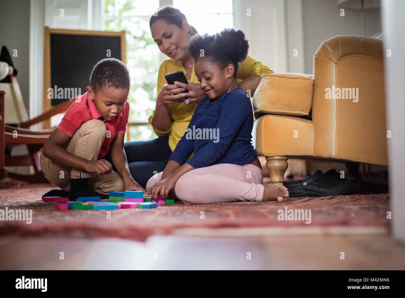 Mom Sie Ihr Smartphone während die Kinder spielen Stockfoto