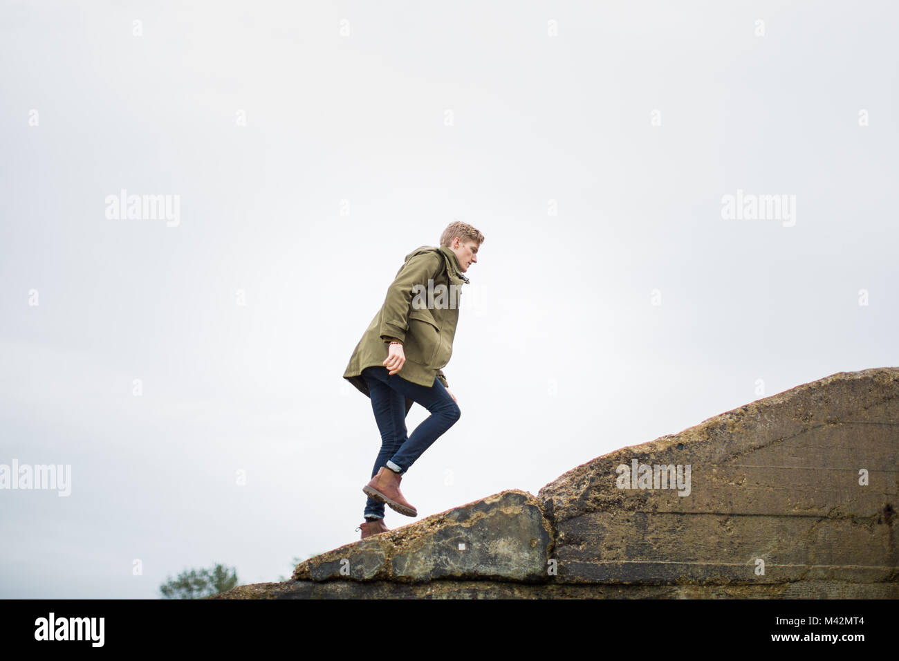 Junge männliche Wandern auf einem steilen Hügel Stockfoto Junge männliche Wandern auf einem steilen Hügel Stockfoto
