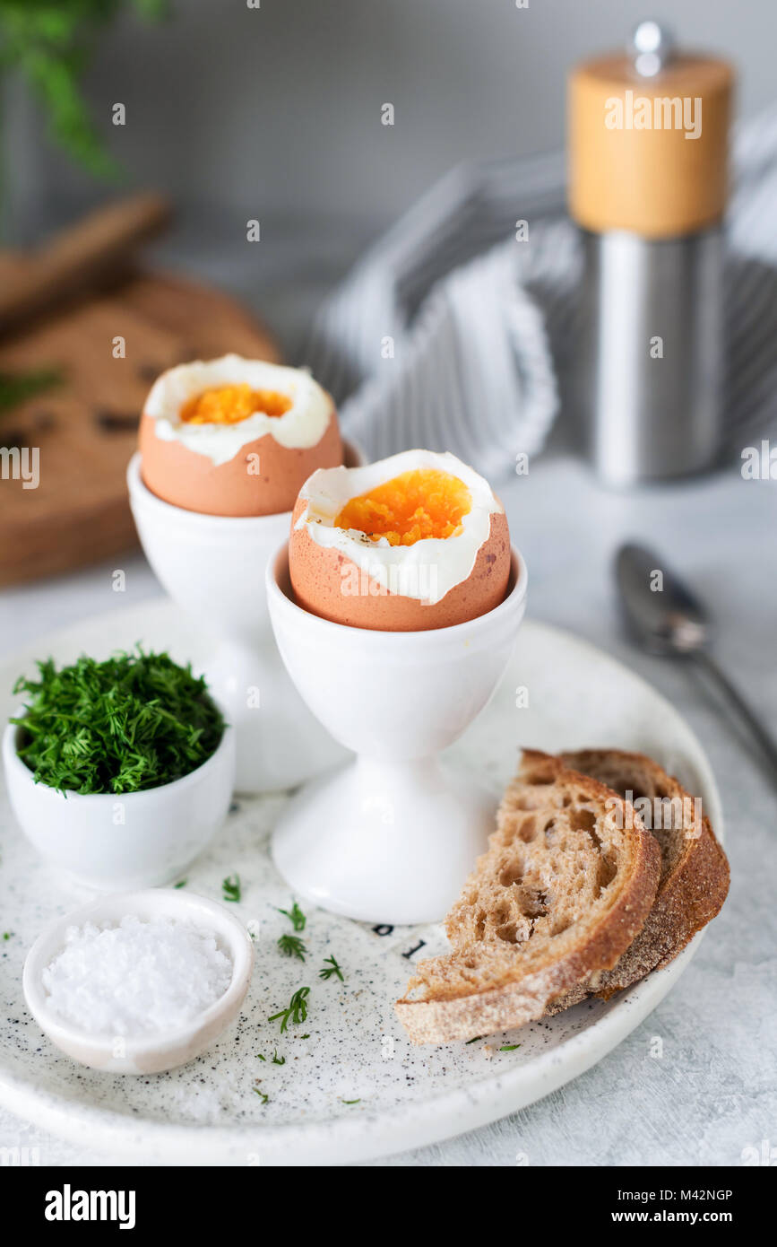 Weich gekochte Eier und Toast zum Frühstück serviert mit Meersalz und gehacktem Dill. Selektiver Fokus Stockfoto