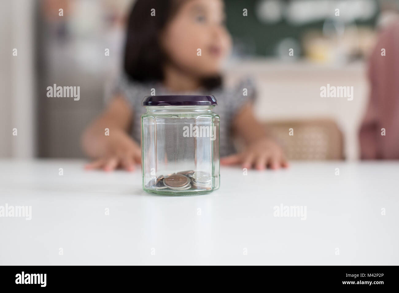 Mädchen speichern ihr Taschengeld in einem Glas Stockfoto