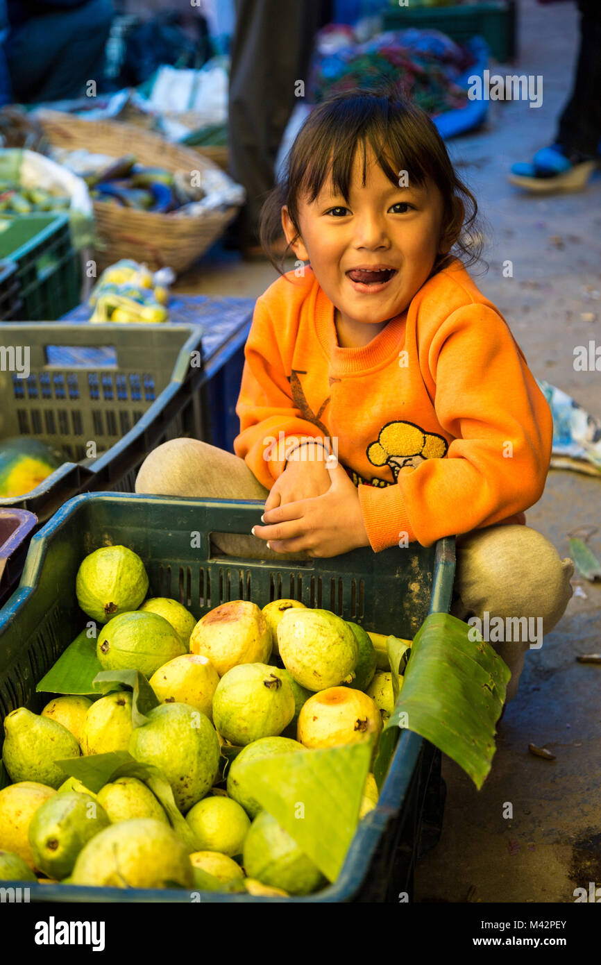 Punakha, Bhutan. Obst- und Gemüsemarkt, kleines Mädchen und Karton mit Melonen. Stockfoto
