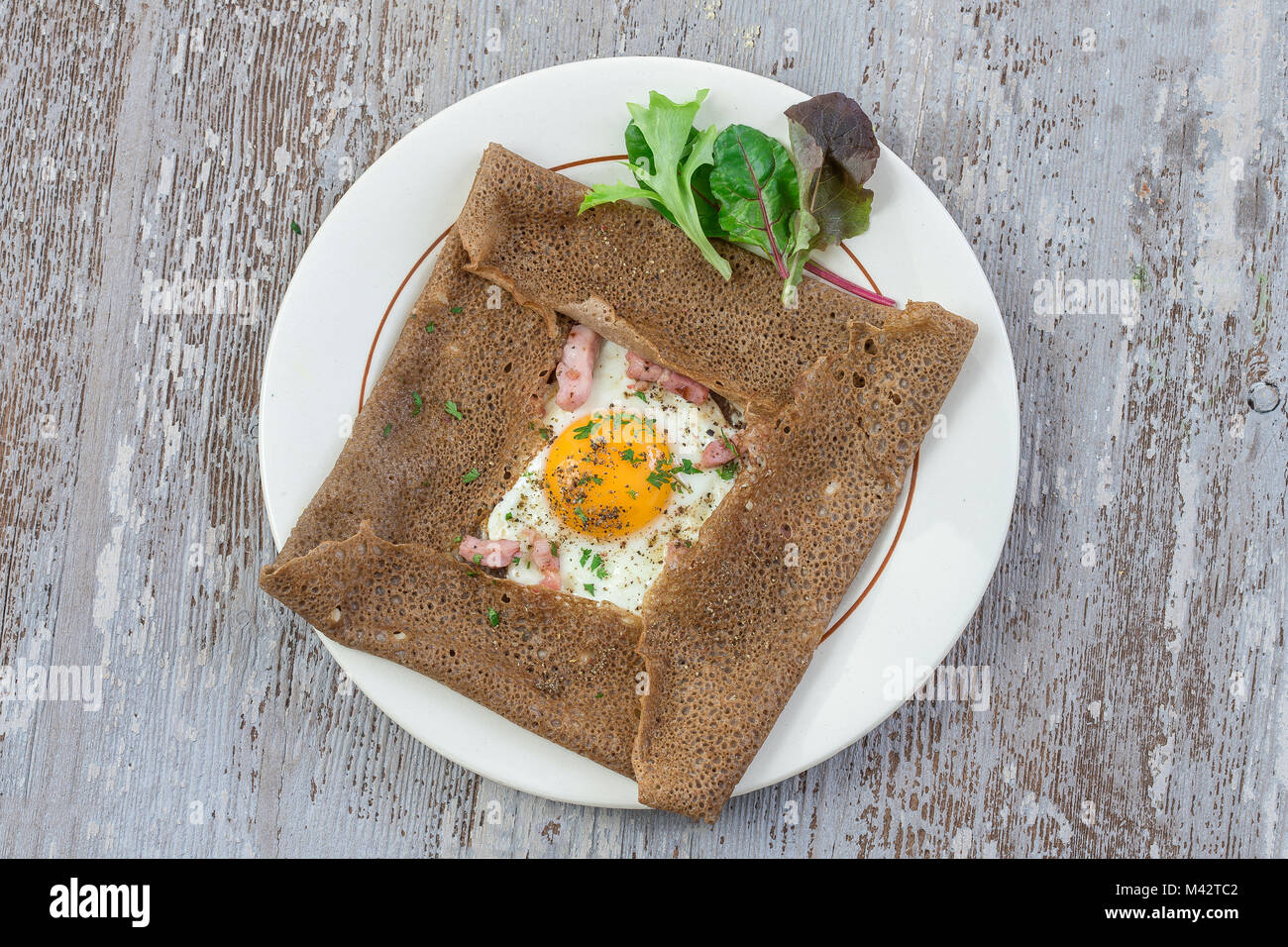 Französische Buchweizen crepe Galette mit Schinken und Ei für leckeres gesundes Mittagessen auf grau Holz- Hintergrund Stockfoto