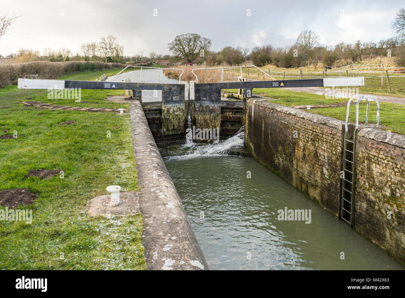 Wasser sprudelt durch eine Kanalschleuse mit Ausgleichsbalken am Kennet und Avon Kanal im Winter in Wiltshire, England, Großbritannien Stockfoto