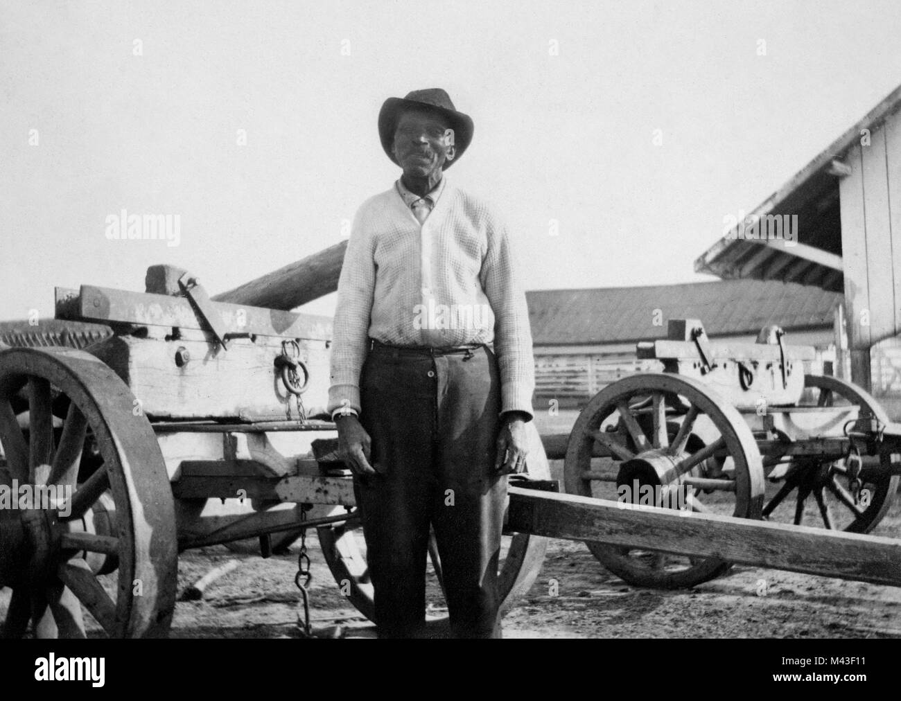 Ein älterer African American man steht vor einem Wagen in den schlammigen Hof von einem Pächter Plantage im amerikanischen Süden, Ca. 1910. Stockfoto
