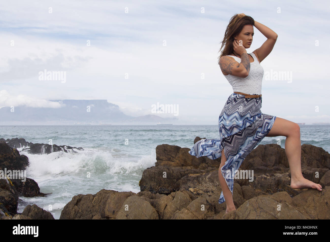 Wunderschöne Frau mit Tattoo auf Felsen am Meer Stockfoto