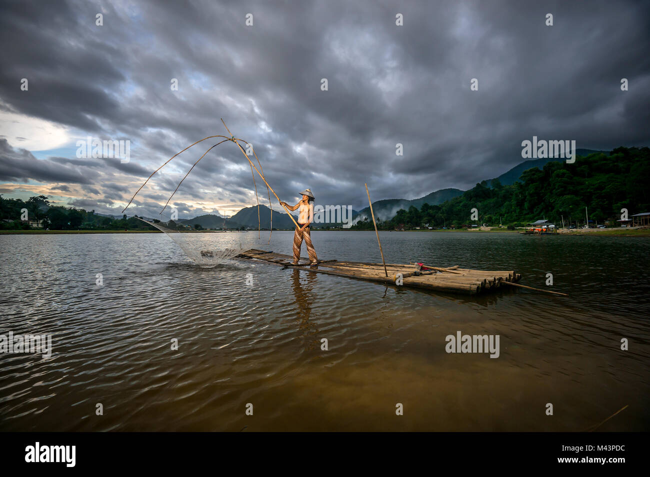 Männer fangen Fische mit traditionellen Werkzeug am See. Stockfoto