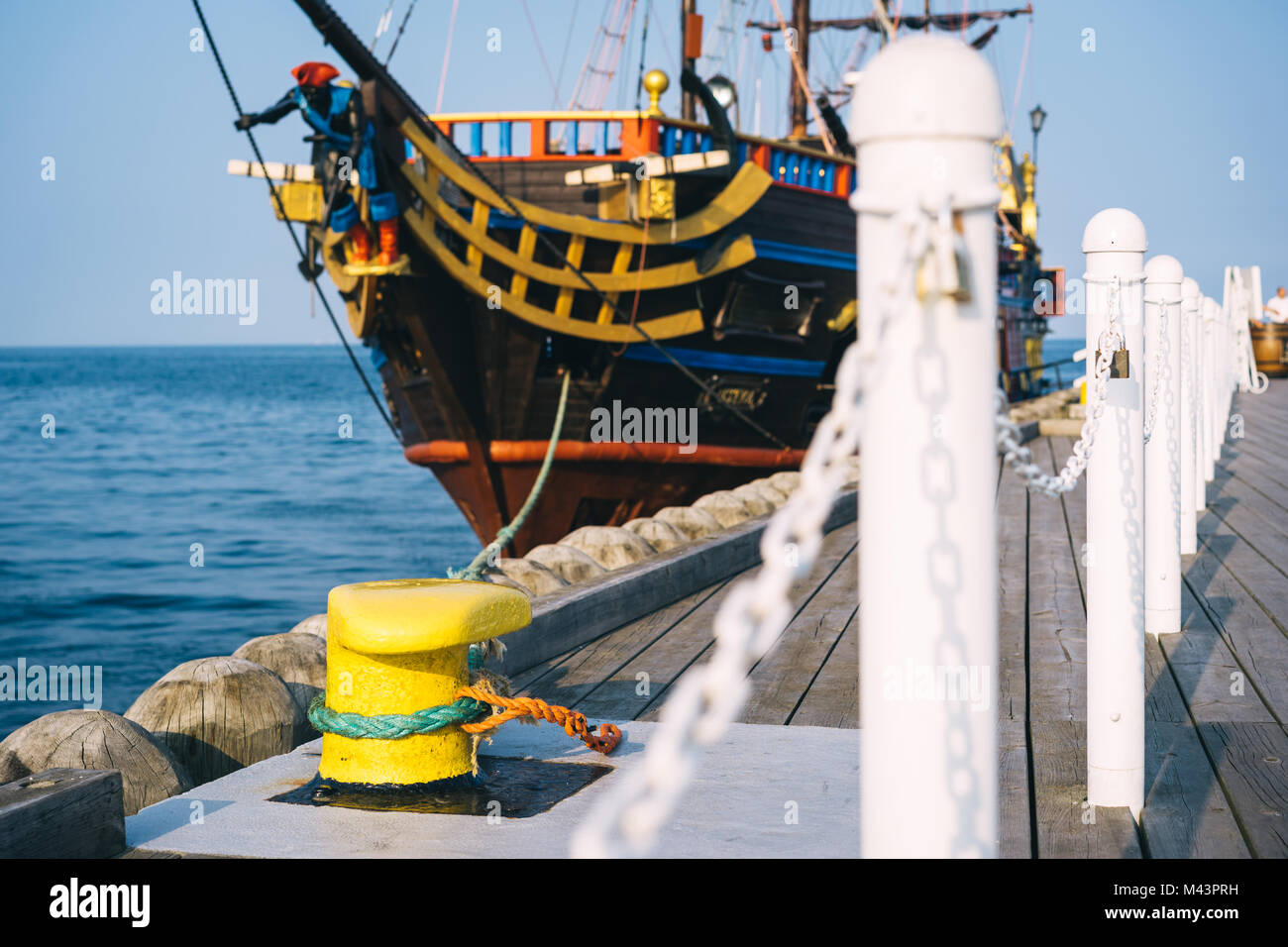 Sopot, Polen. Festmachen Poller auf einem hölzernen Pier mit einem angedockten Piratenschiff im Hintergrund Stockfoto