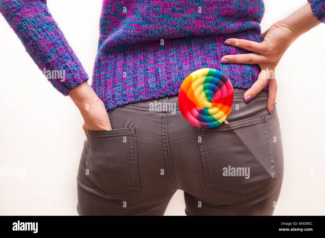 Frau mit lila Pullover und einen Lutscher in die Tasche ihrer Jeans Stockfoto