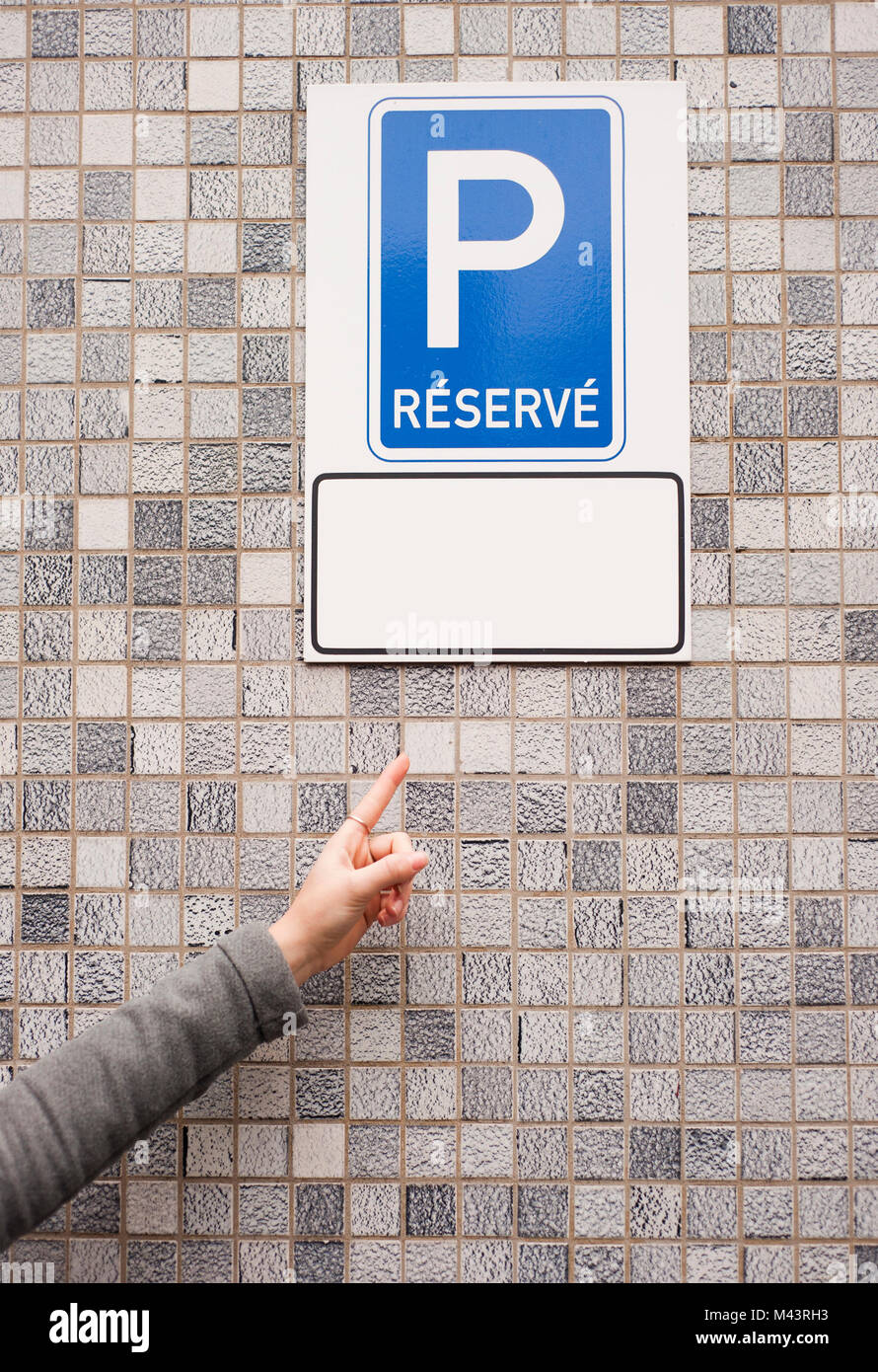 Frau Zeiger in einen reservierten Parkplatz Schild mit einem leeren tag unter es Stockfoto